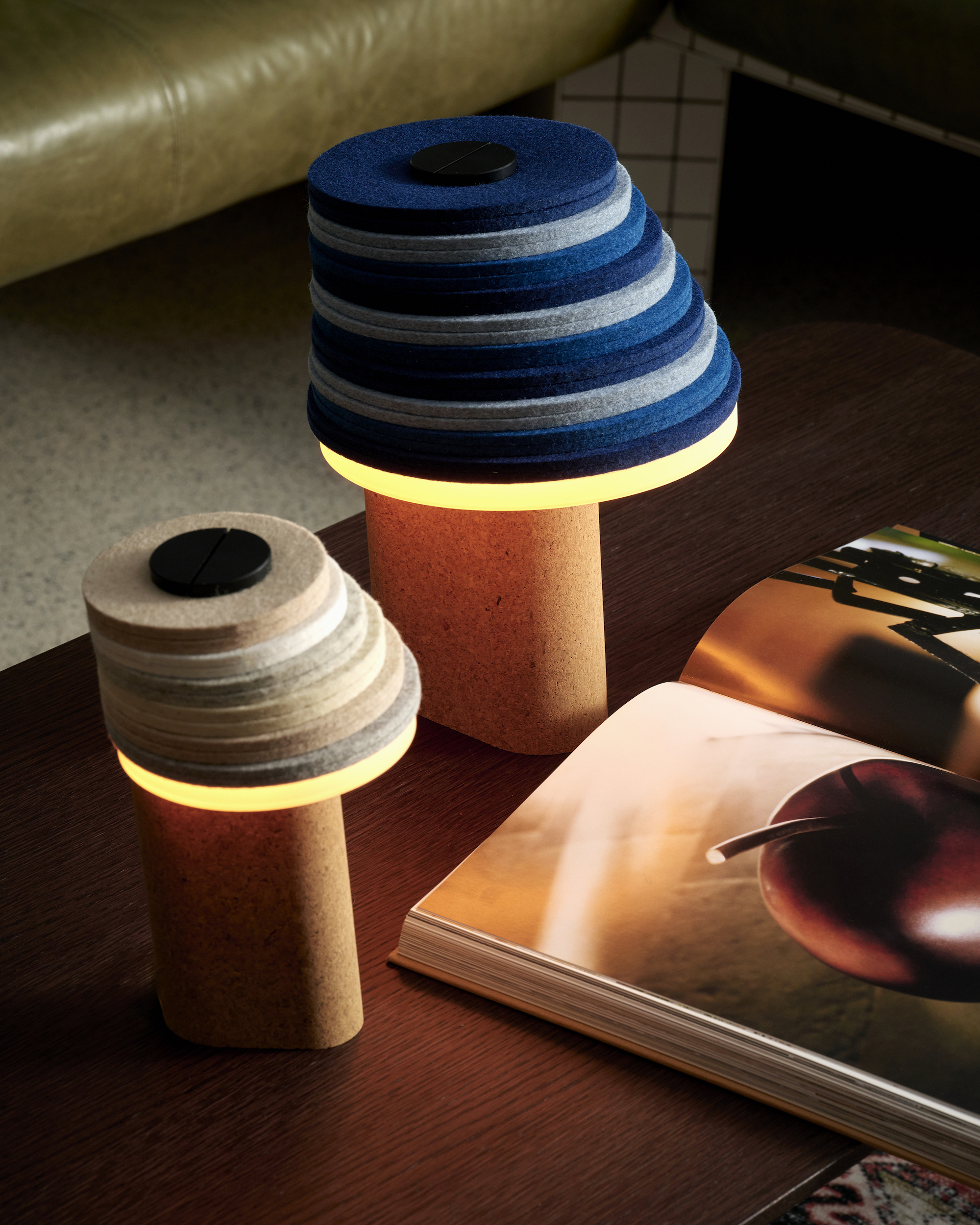 Two lamps, one in neutral shades and the other in blue tones, with stacks of circular disks on top of a beige base, placed on a coffee table. 