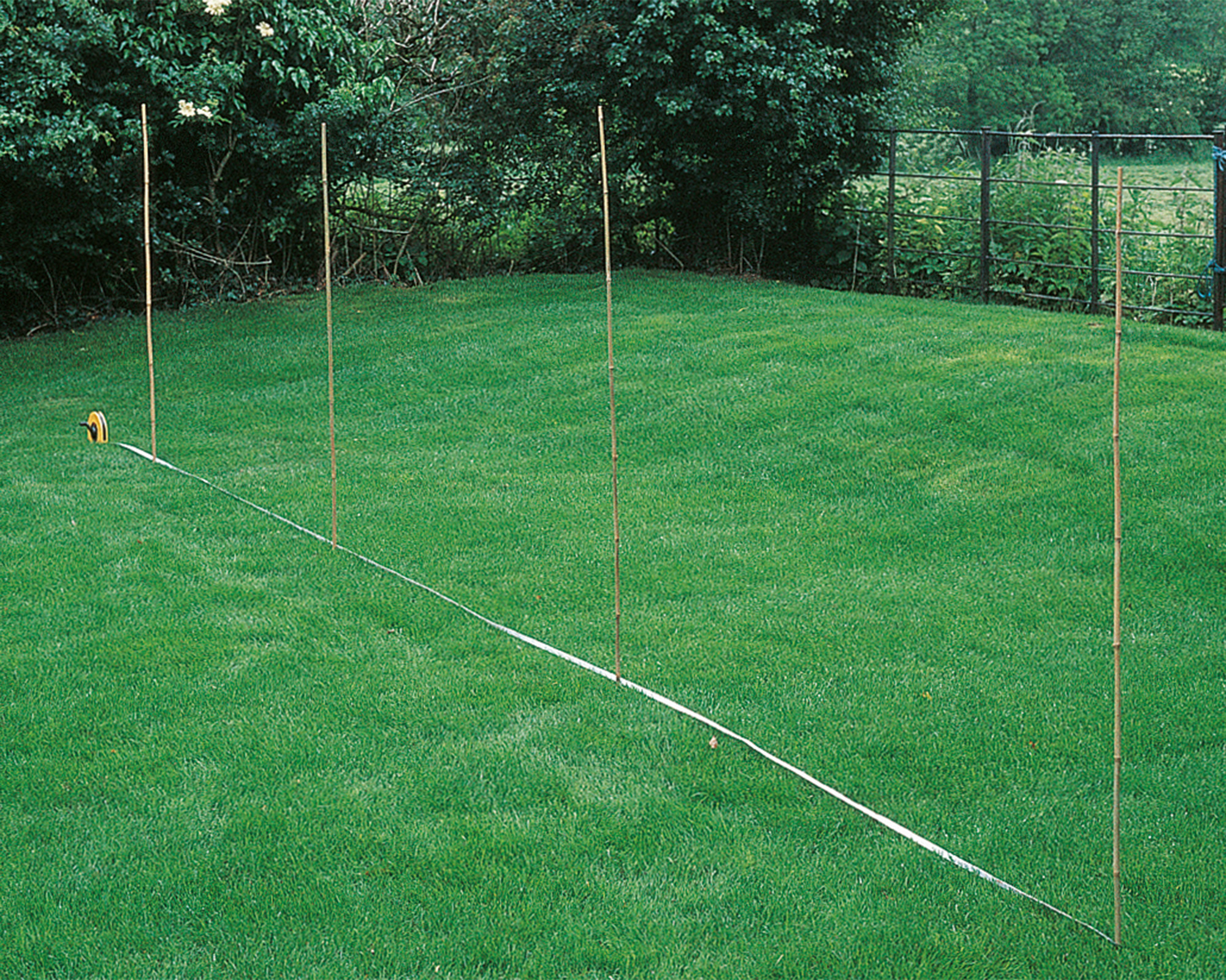 marking out an area with tape and bamboo canes for fence post installation