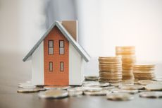 A small toy house sitting amongst coins