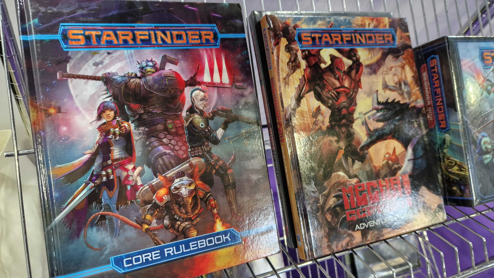 Starfinder books laid out on a wire rack