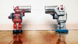 Two toy robots 'talking' to each other via a pair of tin cans connected by a string.