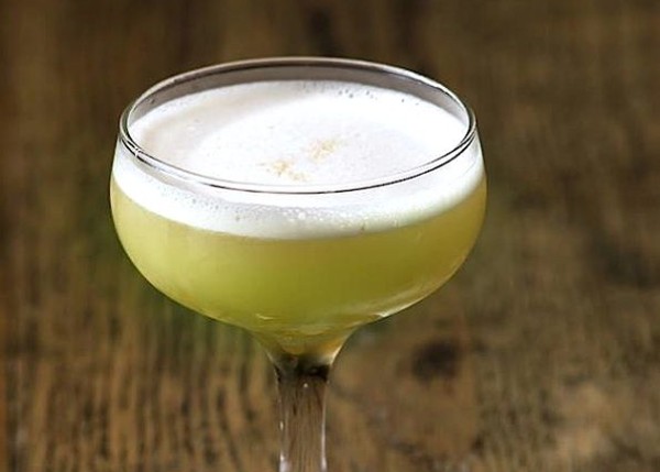 a frothy, dark-yellow cocktail in a coupe