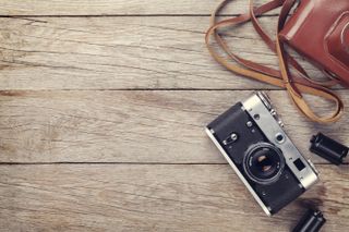 Film camera and roll of film on a wooden table