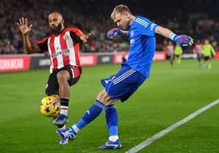 Aaron Ramsdale of Arsenal clears under pressure from Bryan Mbeumo of Brentford during the Premier League match between Brentford FC and Arsenal FC at Gtech Community Stadium on November 25, 2023 in Brentford, England.