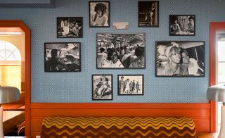 Black & white photos of black female models are hung on the wall, which is light blue with white dots.