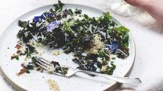 Kale and edible flower salad with pecorino crisps on a plate with a fork
