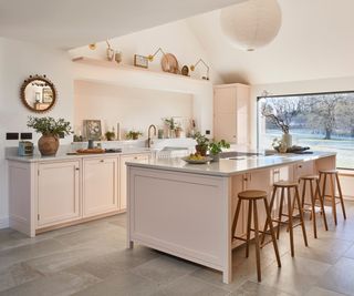 pale pink fitted kitchen in room with tiled floor, large picture window and vaulted ceiling