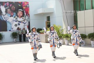 The three astronauts of China's Shenzhou 9 crew, the fourth human spaceflight for the country, wave to cheering supporters as they walk out to their Shenzhou 9 spacecraft before launching on June 16, 2012, from the Jiuquan Satellite Launch Center. The crew is Liu Yang, China's first female astronaut (left); Jing Haipeng, mission commander (center);and Liu Wang.