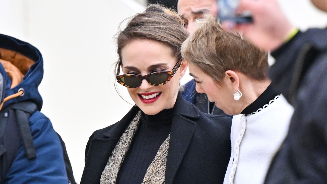 Natalie Portman wearing a tweed suit with oval sunglasses and a black coat 