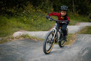 A kid on a Vitus bike riding on a pump track
