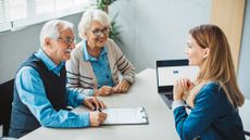 An adviser meets with an older couple in her office.