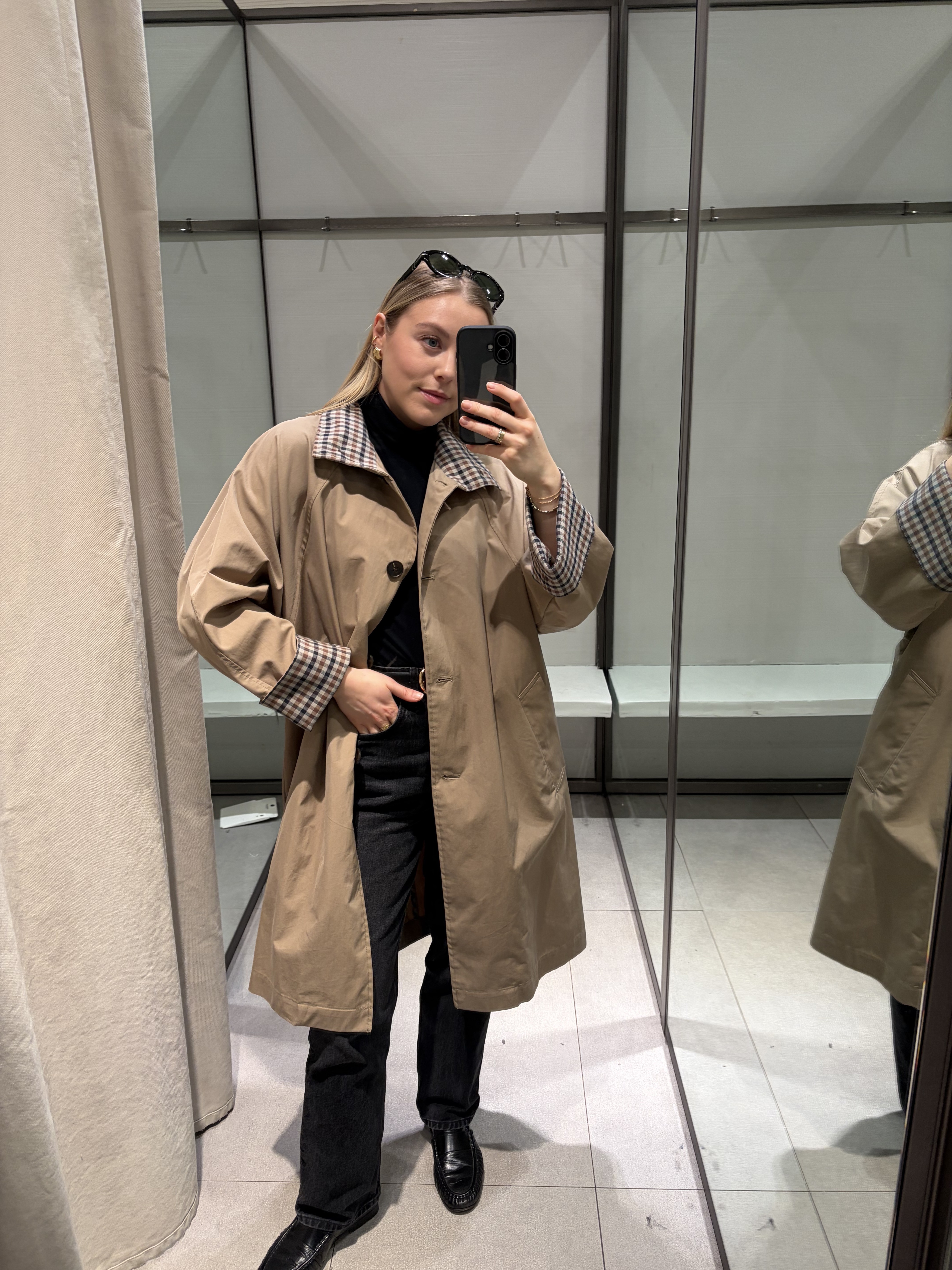 Woman wears beige trench coat, black jeans, black loafers