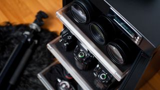 Cameras and lenses on the shelves of an open dry cabinet