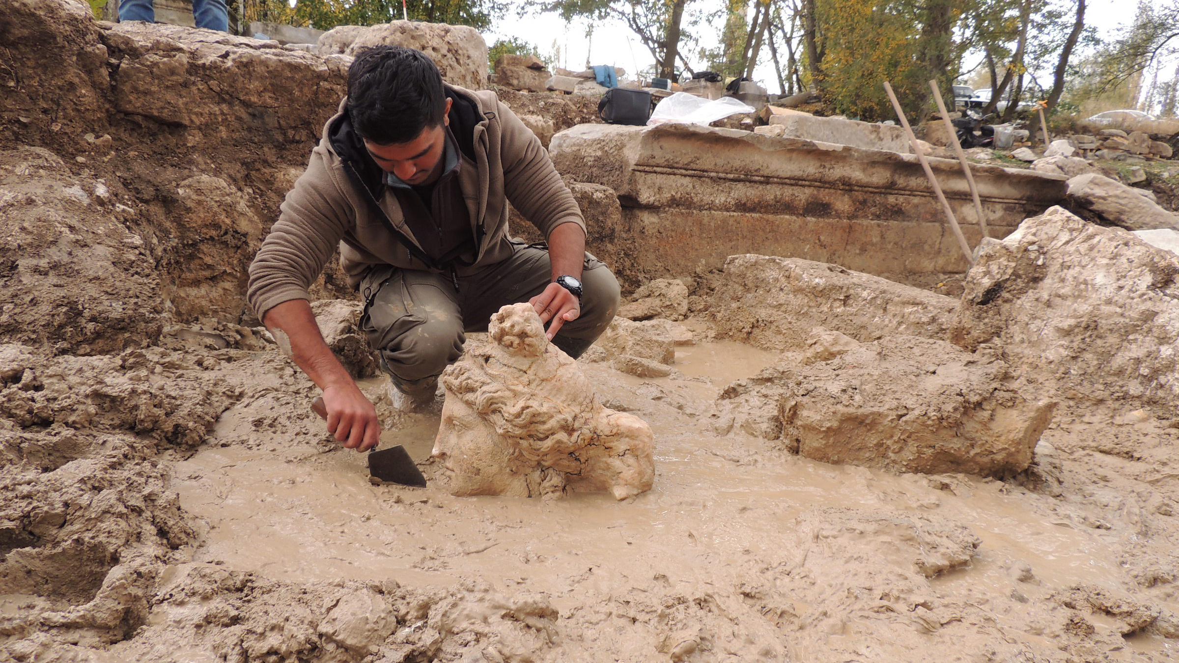 Ein Archäologe gräbt den Kopf der Aphrodite aus dem Dreck.