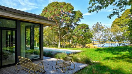 The backyard of a home with two patio chairs and a home with a flat roof. 