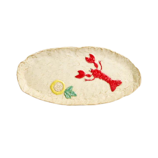 Cream colored, rough edges serving dish, featuring a lobster and a lemon design