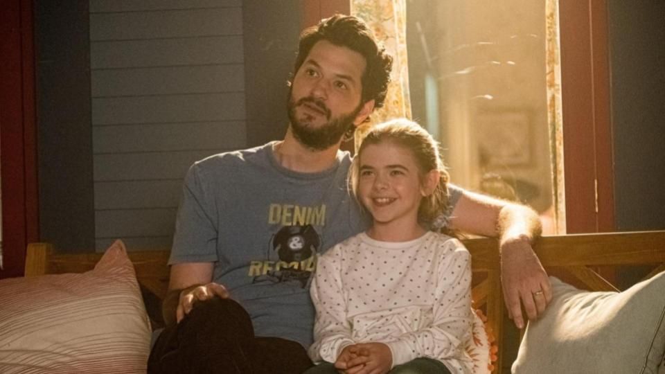 George and his daughter Flora sit on a sofa embracing