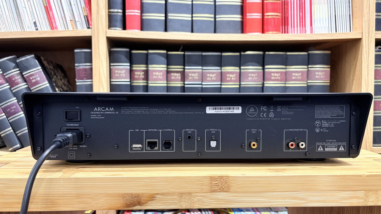 Arcam ST25 music streamer on wooden rack with bookshelf behind it