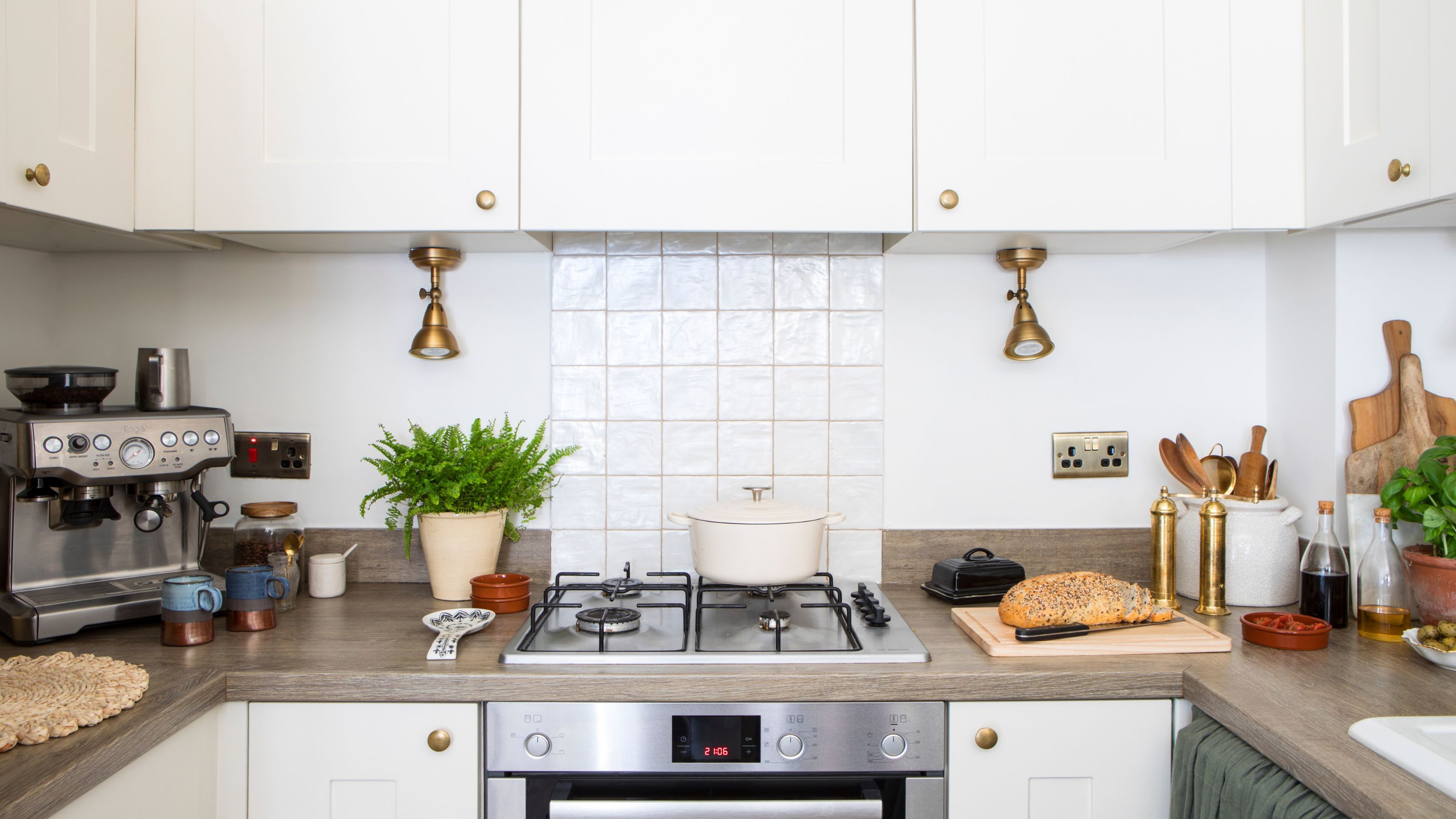Galley kitchen with white cabinets and a lot of food and cooking items on the wooden worktops