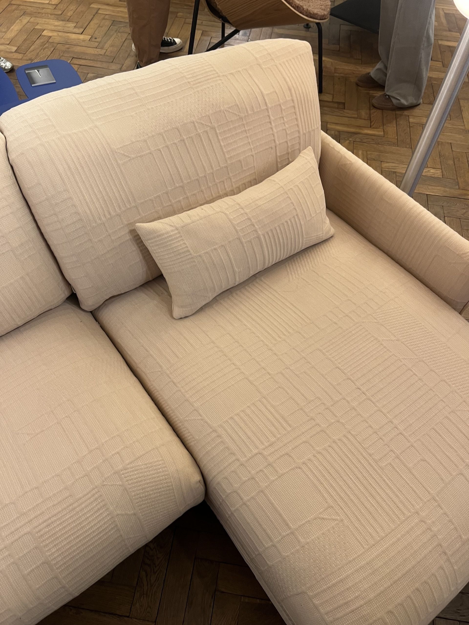 Close-up, overhead image of a pale peach sectional sofa that has a subtle geometric texture.