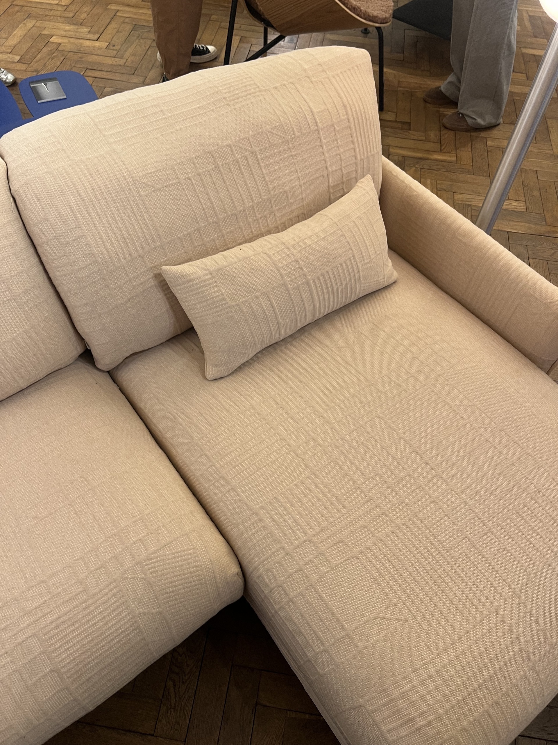 Close-up, overhead image of a pale peach sectional sofa that has a subtle geometric texture.