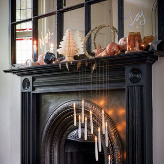 Living room with black mantelpiece decorated with Christmas decorations and hanging candles