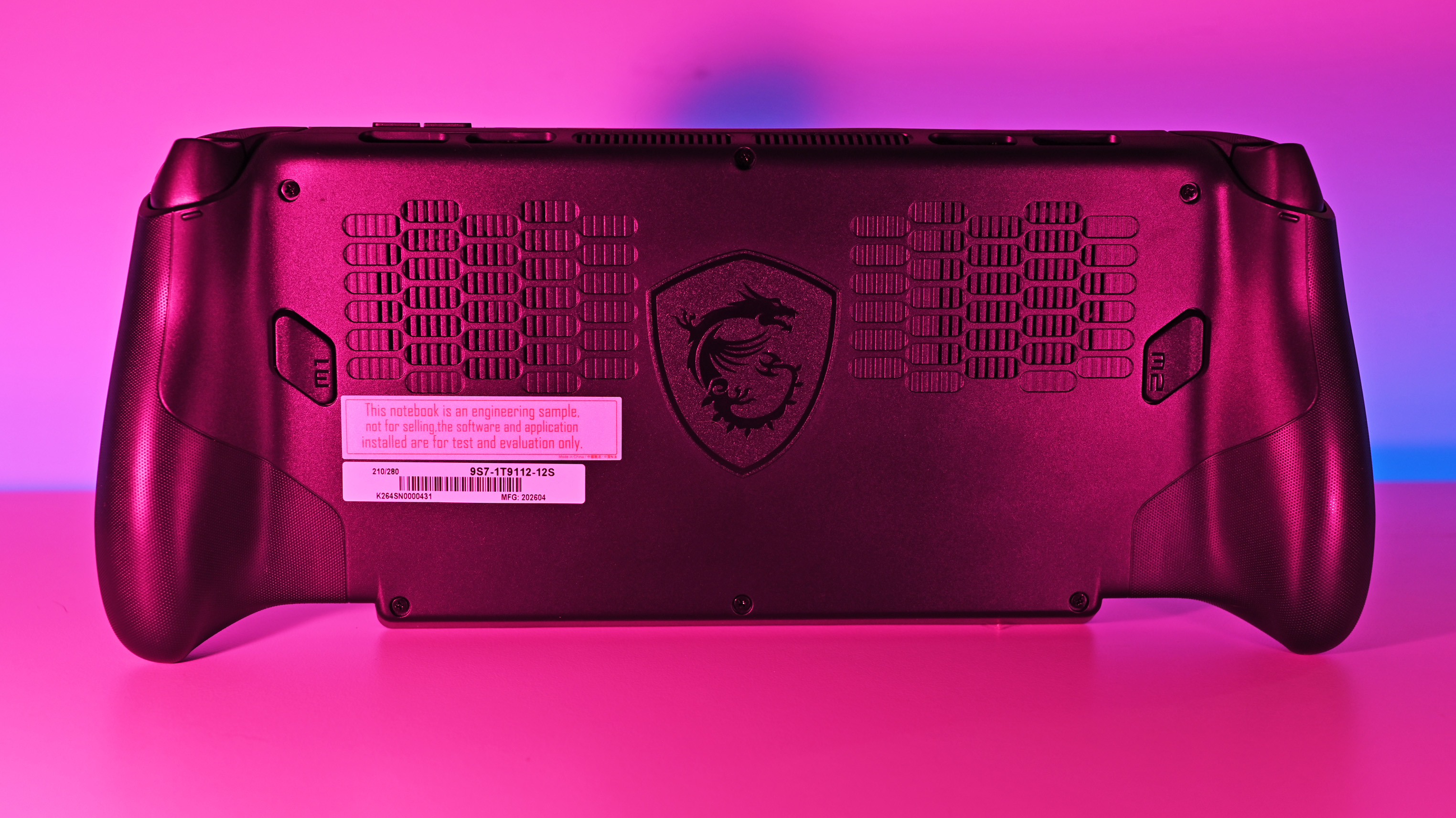 Rear view of the MSI Claw 8 EX AI+ chassis under pink illumination, showcasing dual intake vent arrays, the signature MSI dragon crest logo, and M1 and M2 macro buttons.
