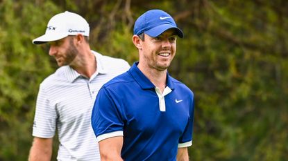 Rory McIlroy smiles in front of Dustin Johnson