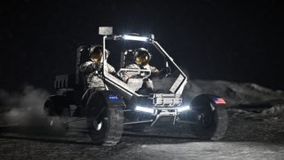 two astronauts in a four-wheeled vehicle on the moon