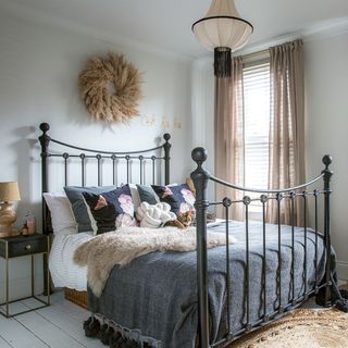 white bedroom with cast iron bed and grey cover