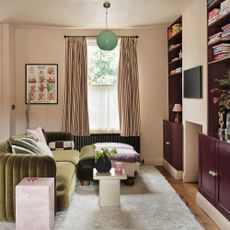 a small living room with a green velvet sofa and dark burgundy fitted alcove shelving and cabinetry