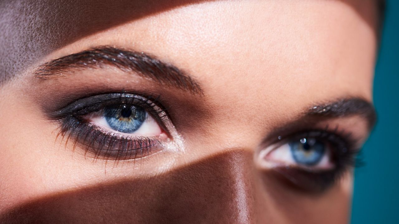 close-up of a woman&#039;s blue eyes with a shadow running across her face