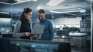 Two colleagues looking at laptop screen, happy to be protected by ESET