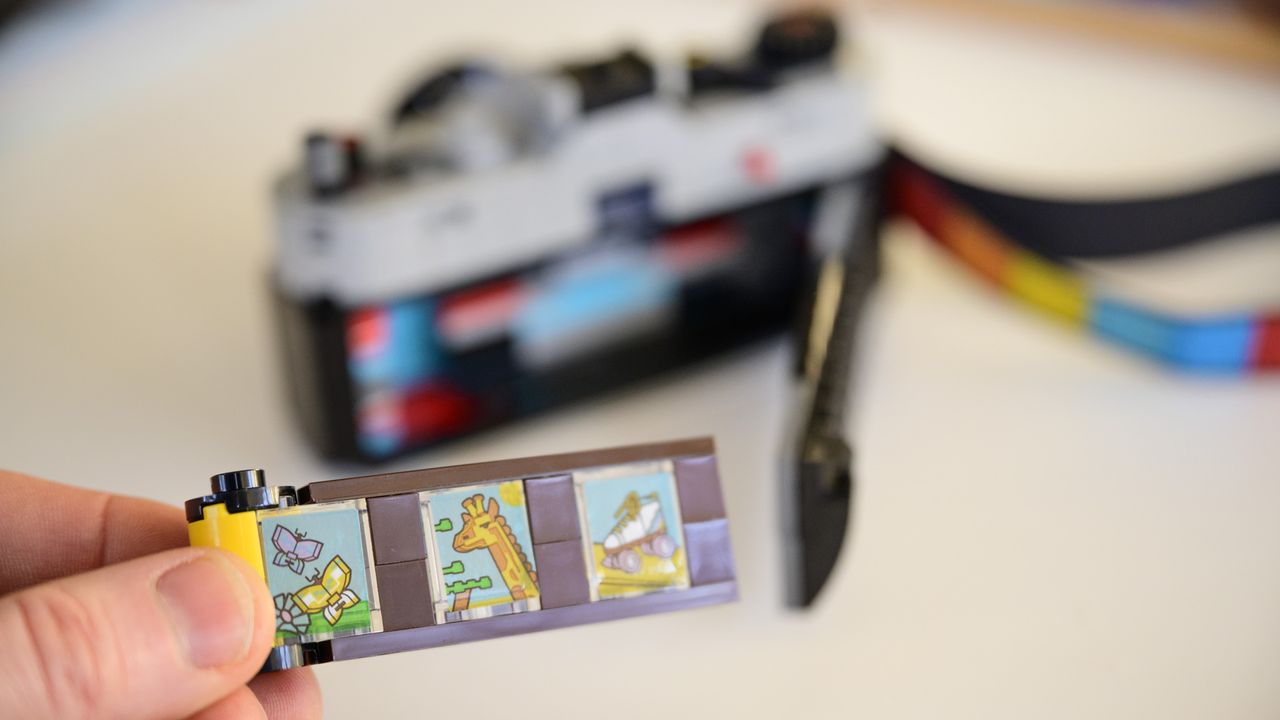 Lego Retro camera film cannister in front of open film door on the camera's rear