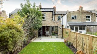a victorian terrace extension with a white patio and a green lawned garden by Jody Stewart
