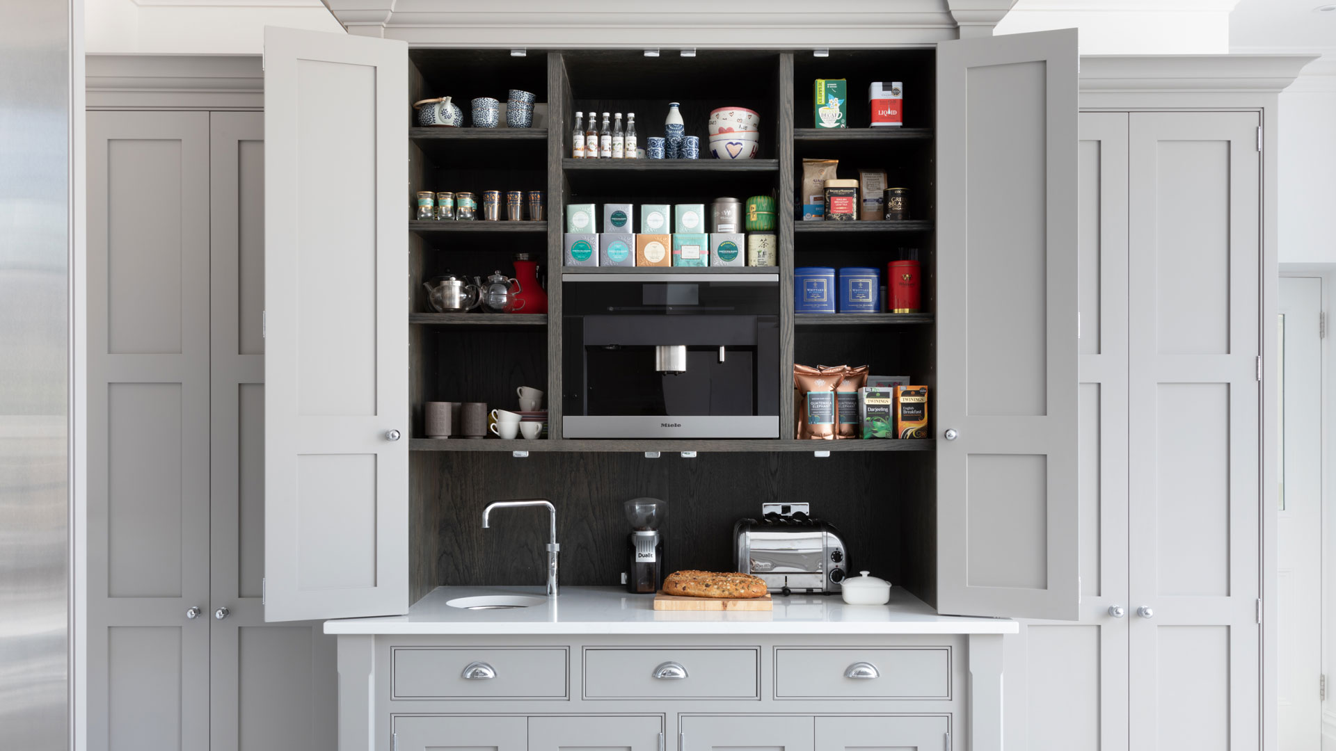 grey kitchen larder unit with built-in coffee machine and small sink with toaster