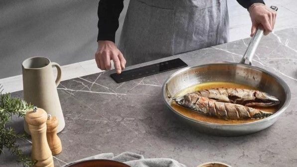 An invisible hob on a granite kitchen surface with a small black panel