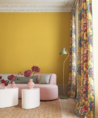 A living room curtain idea with yellow walls, pink sofa and yellow floral curtains