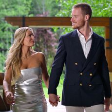 Theresa Demaria and John Merrill walk down a bridger wearing formal wear in a still from age of attraction