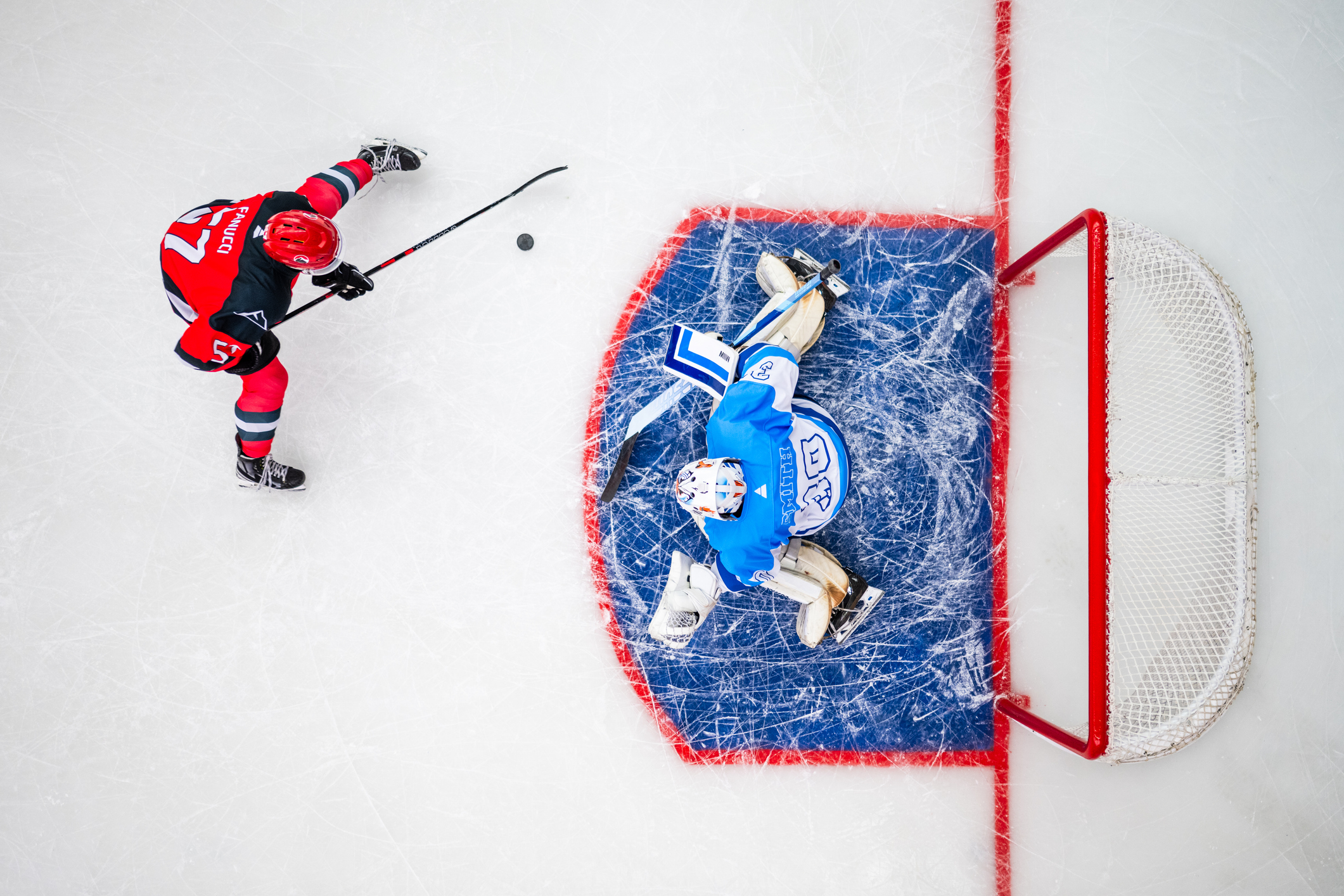 Birdseye view of an ice hockey player about to shoot into a goal with goalie defending. 
