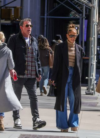 Jennifer Lopez styles wide-leg puddle jeans with platform heels.