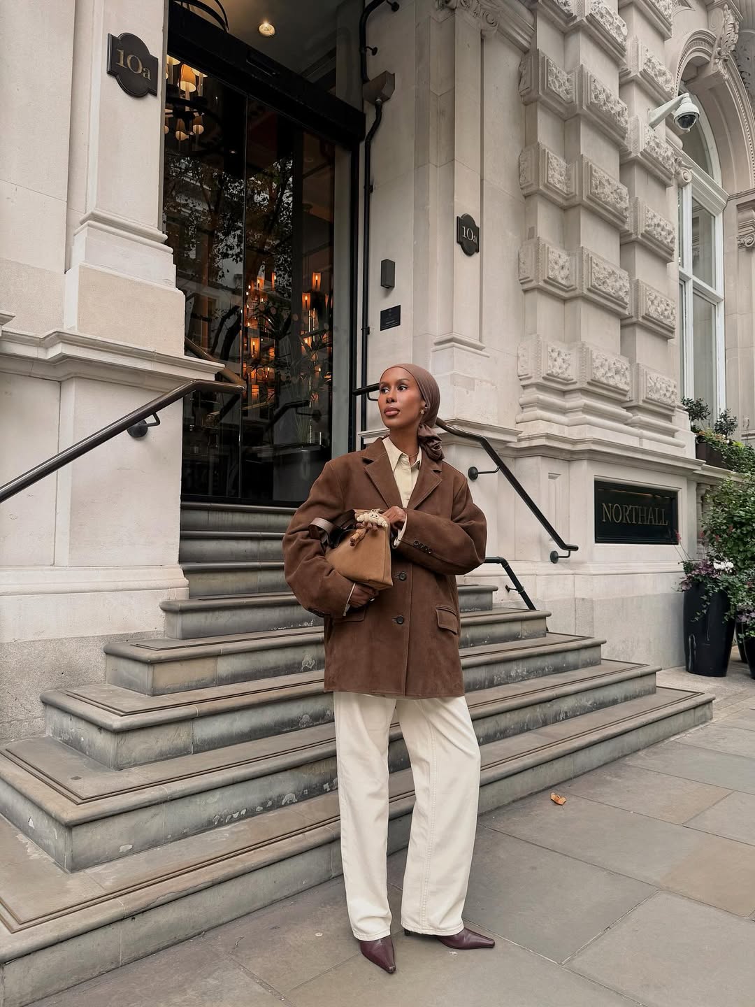 @basma_k wears cream jeans, brown boots, suede brown blazer