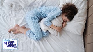 A woman in white and blue stripped pajamas sleeps on a white mattress
