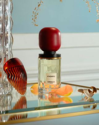 Ormaie bottle of Yvonne fragrance a glass countertop against a light blue wall