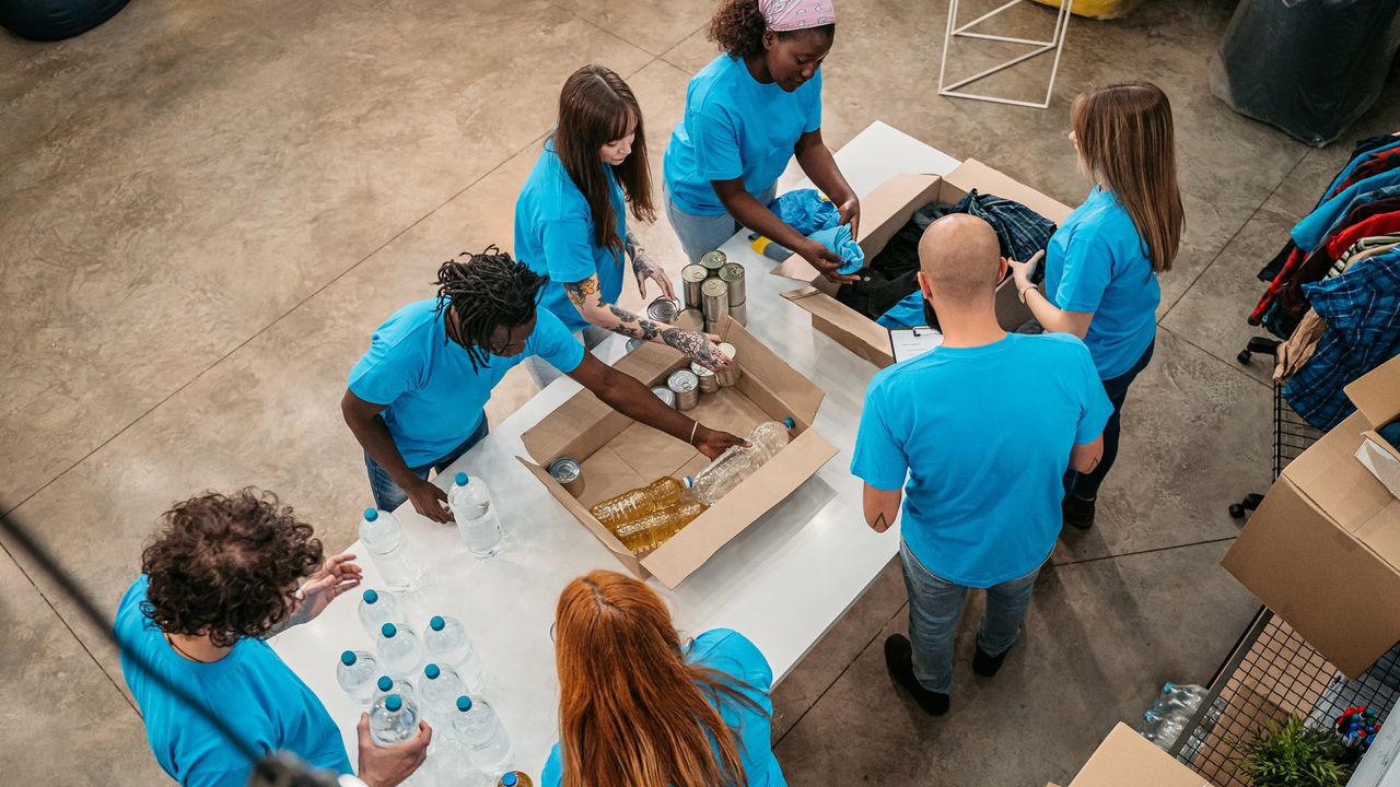 A group of volunteers fill boxes with clothing and other necessities.