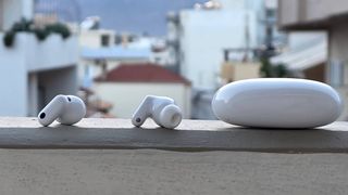 The Huawei FreeBuds Neo buds and case on a ledge, in front of a city.