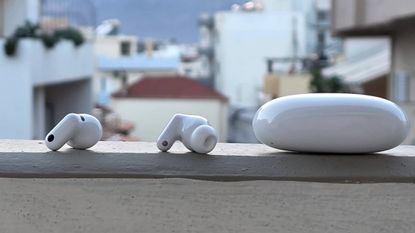 The Huawei FreeBuds Neo buds and case on a ledge, in front of a city.