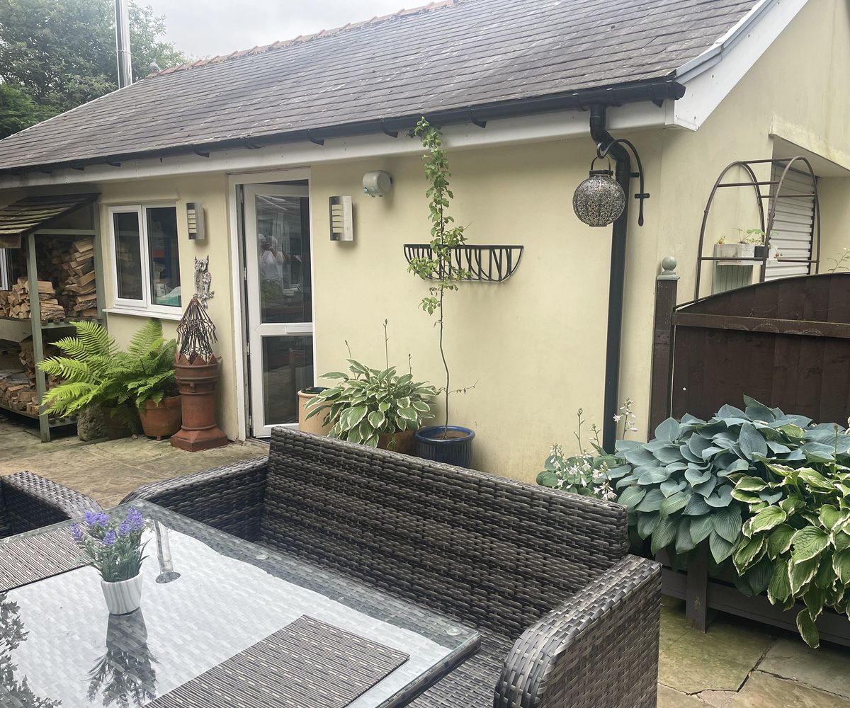 Photo of a plain single storey wall of a house with garden furniture in front