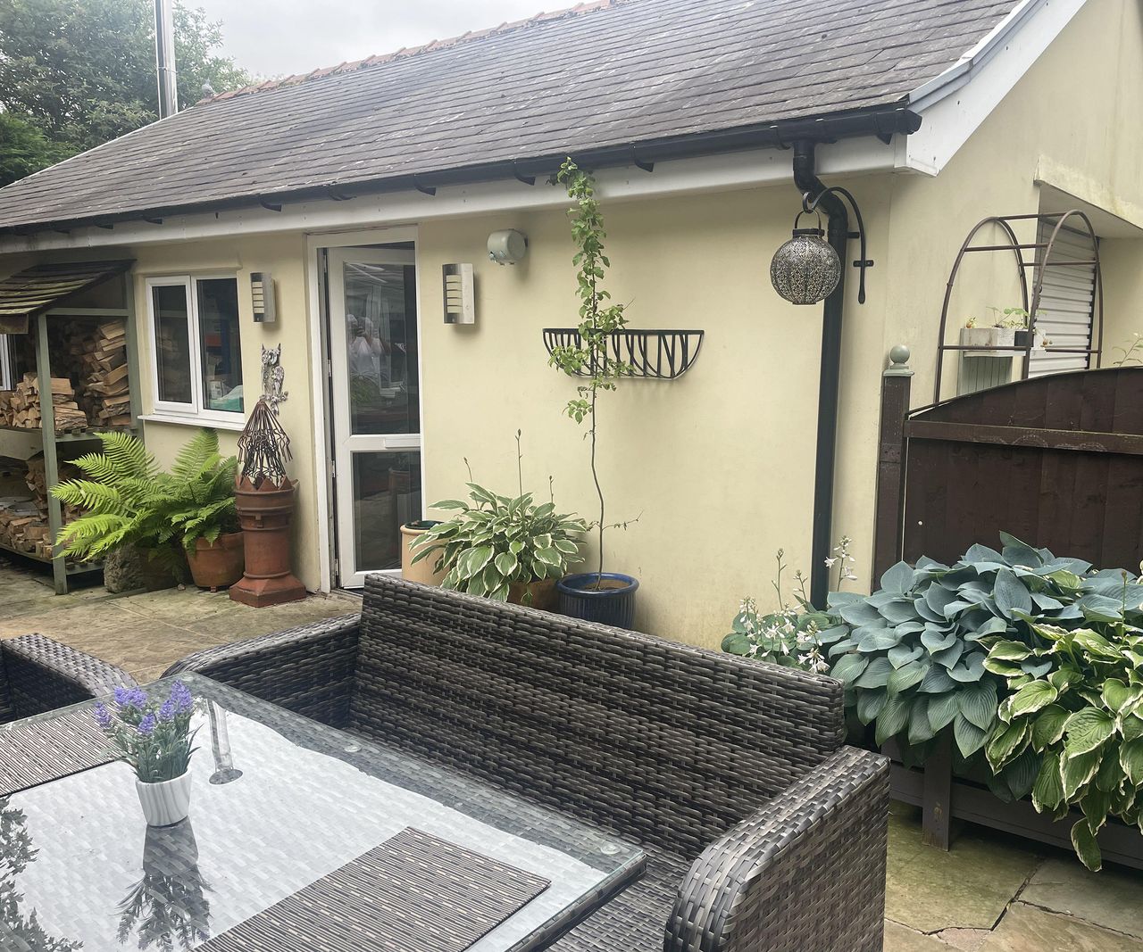 Photo of a plain single storey wall of a house with garden furniture in front