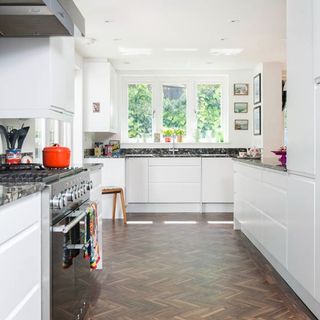 kitchen with white wall wooden flooring and white cabinets